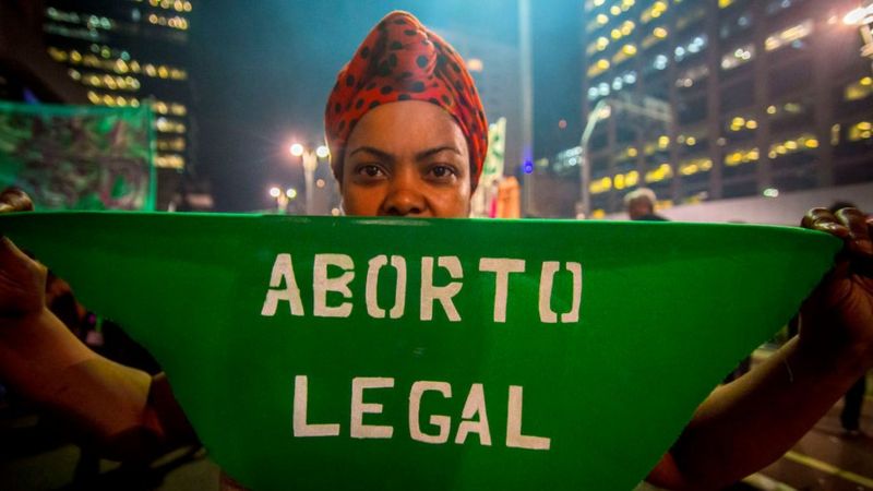 Mulher segura faixa verde onde lê-se "Aborto legal". Foto: Getty Images