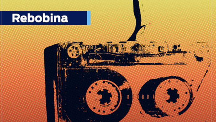 Imagem de uma fita cassete com filtro degradê vermelho e amarelo. No topo, do lado esquerdo, em letras pretas, "Rebobina"
