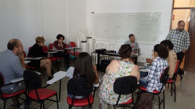 Equipe da Frei Caneca FM reunida sentados em sala de aula, Kosta Kostov, encontra-se sentado à frente da plateia que acompanha a fala.