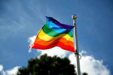 Bandeira do Orgulho LGBTQI+ com o sol ao fundo.